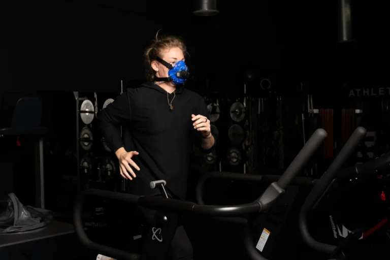 Athlete running on a treadmill in a gym while wearing a SpiroFit metabolic analyzer mask