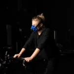 Athlete on an exercise bike in a dark gym wearing a SpiroFit metabolic analyzer mask