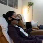 Woman reclining in a chair during a resting metabolic rate test with a SpiroFit mask